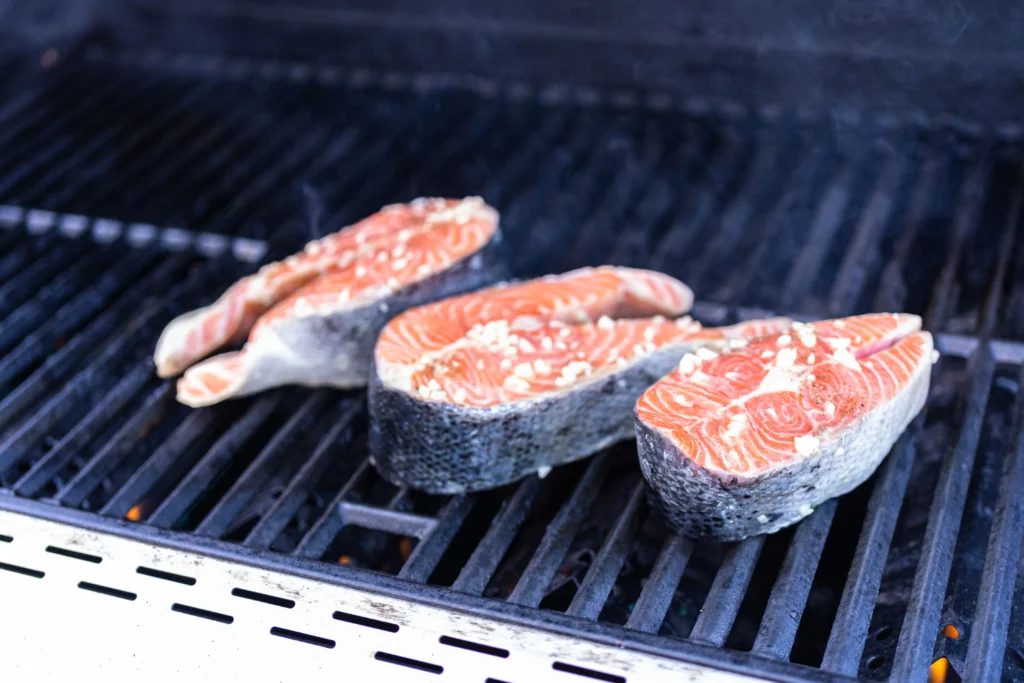 Grilling King Salmon fillets on a cedar plank over an outdoor grill