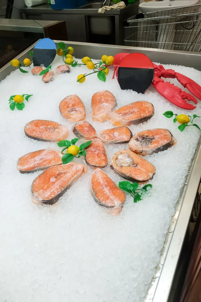 Fresh Wild-Caught King Salmon fillets on ice at a fish market