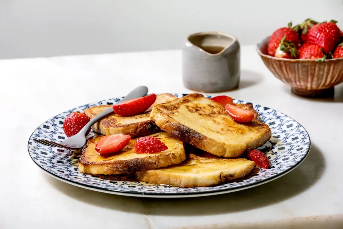 Slices of golden-brown sourdough French toast topped with fresh berries