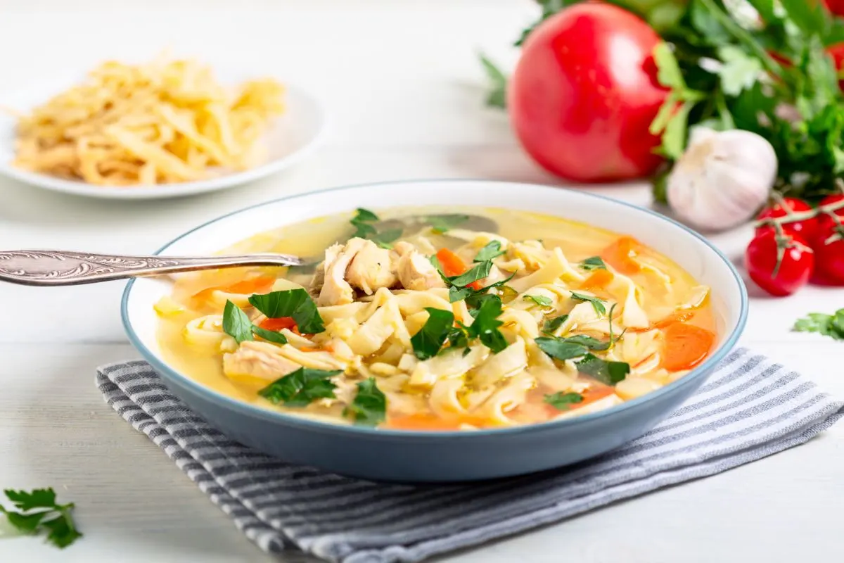 Bowl of vegan chicken noodle soup with fresh herbs